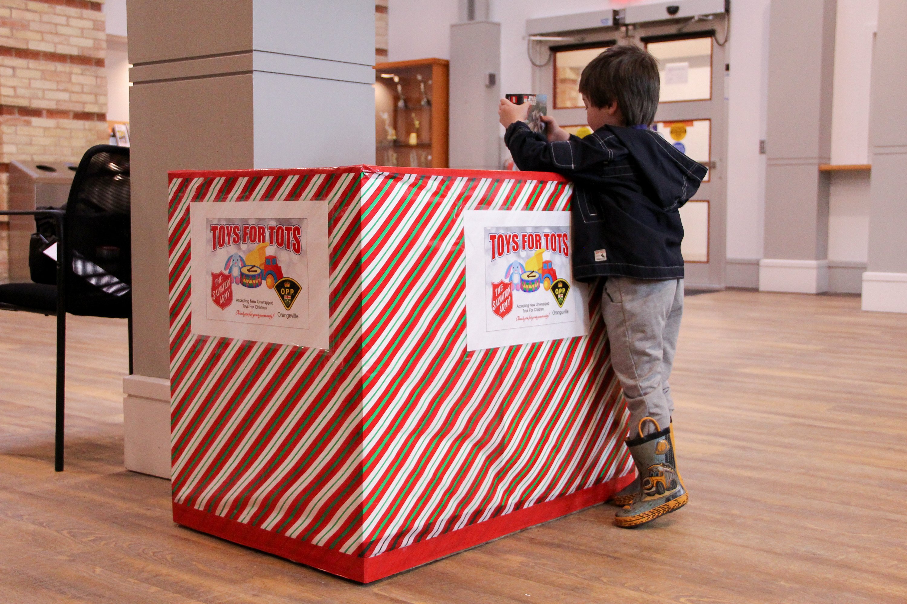 A child drops a toy donation in a Toys for Tots donation box